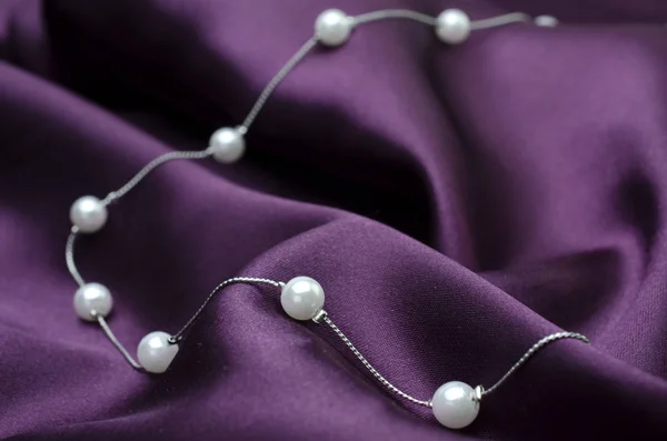 silver necklace chain with pearls isolated on silk