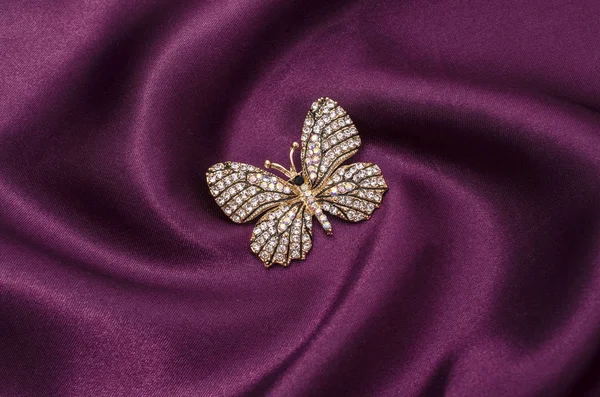 Broche mariposa dorada con diamantes en tela de seda — Foto de Stock