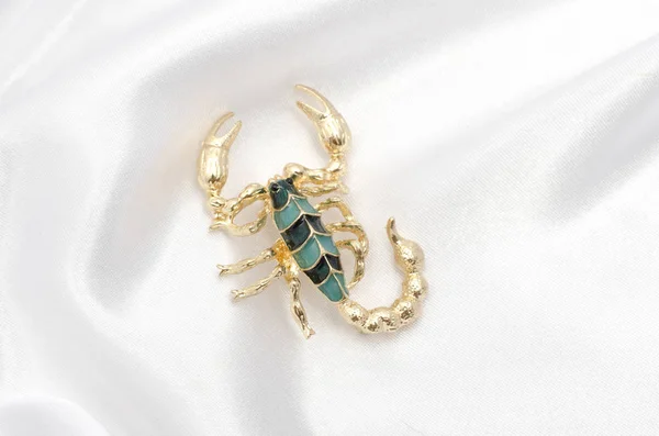 Brooch gold scorpion on white silk — Stock Photo, Image