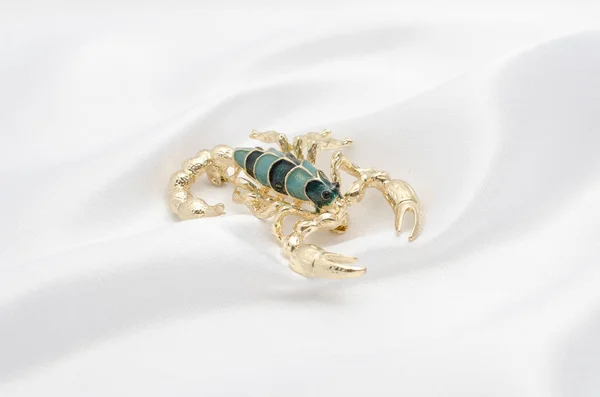 Brooch gold scorpion on white silk — Stock Photo, Image