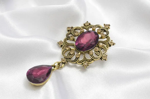 Gylden vintage broche med purpurrød sten på silke - Stock-foto