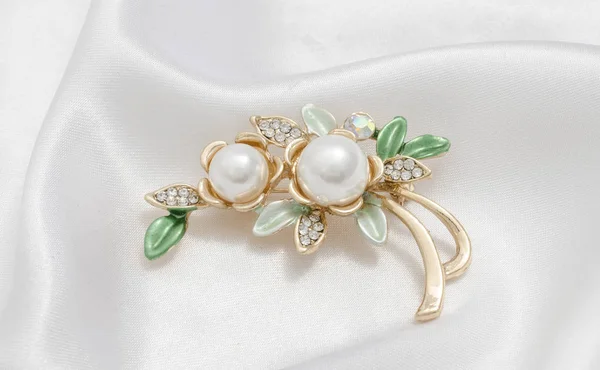 シルクの背景に真珠と金のブローチ花 — ストック写真
