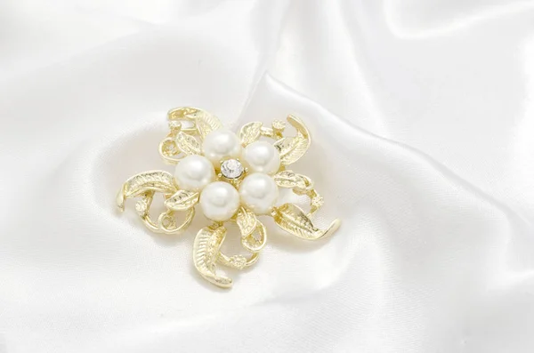 Gold brooch flower with pearl on silk background — Stock Photo, Image