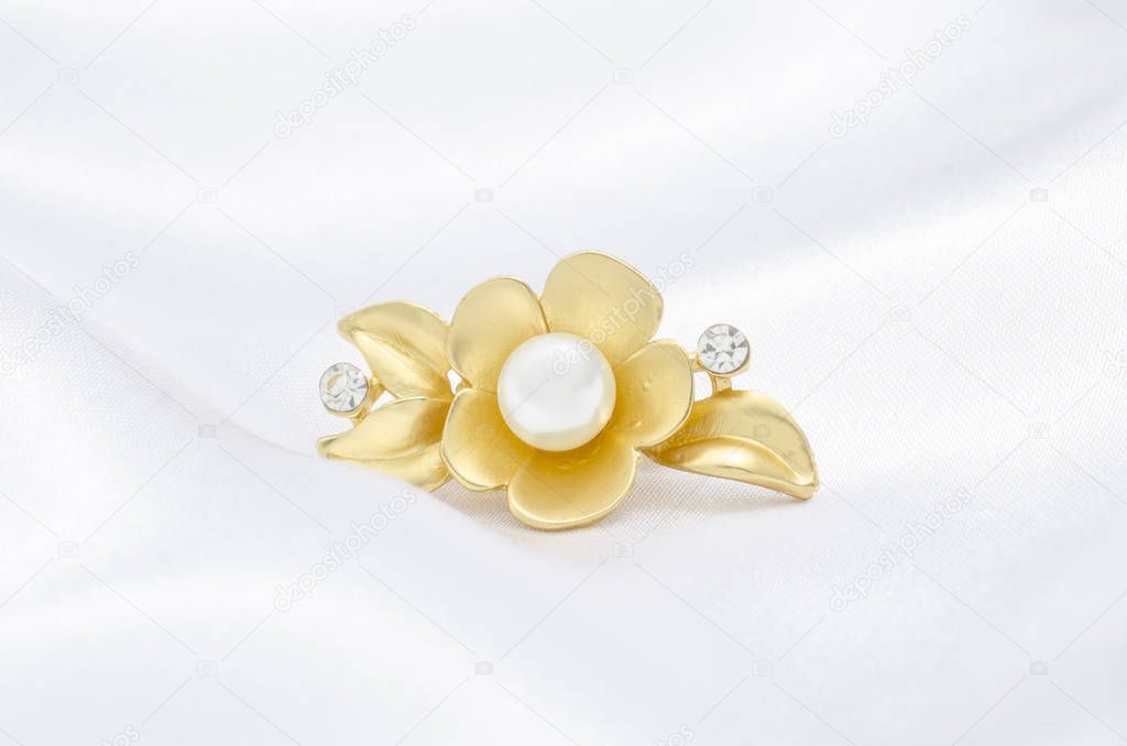 gold brooch flower with pearl on silk background