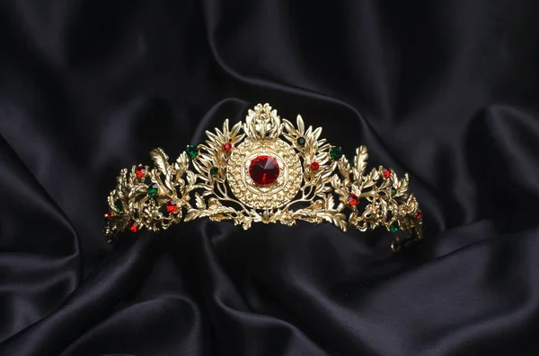 Coroa dourada com rubis em uma seda preta — Fotografia de Stock