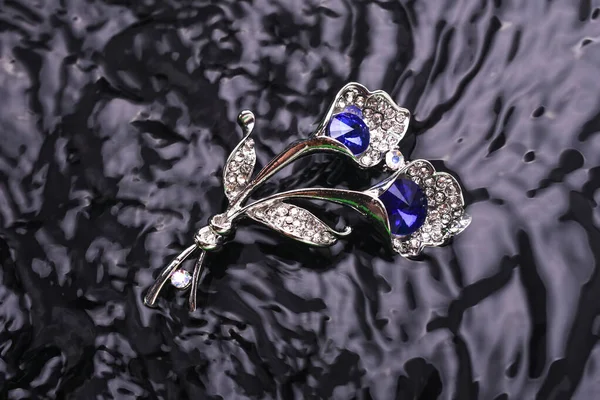 Silver brooch flower with blue stone in the water — Stock Photo, Image