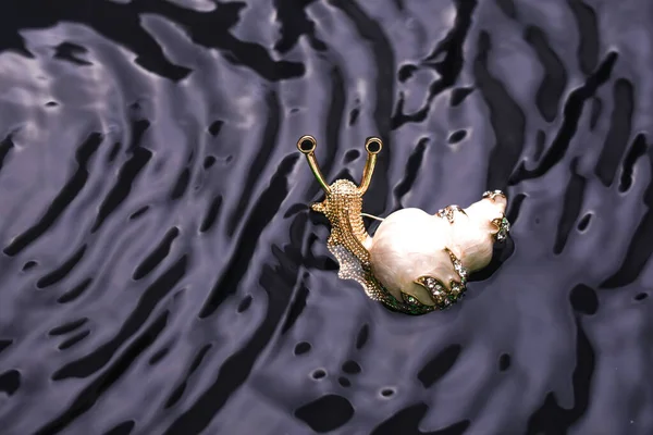 Caracol de broche de esmalte de ouro com diamantes na água — Fotografia de Stock