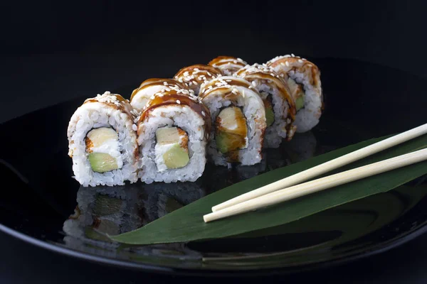 Japanische Sushi-Rollen mit Aal, Tofu und Avocado auf schwarzem Teller — Stockfoto