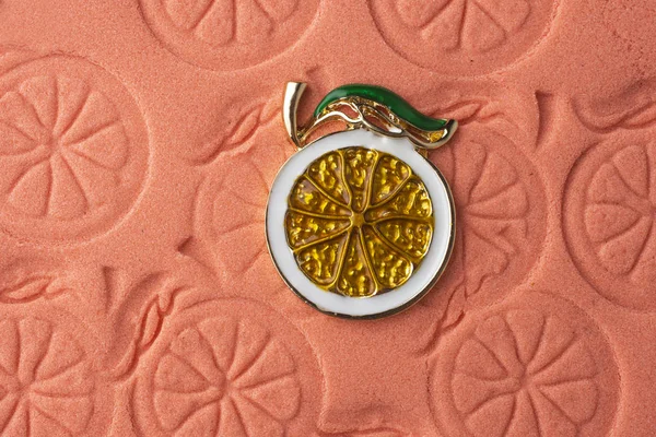 Lemon enamelled brooch on the pink sand Royalty Free Stock Images