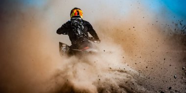 ATV rider creates a large cloud of dust and debris clipart