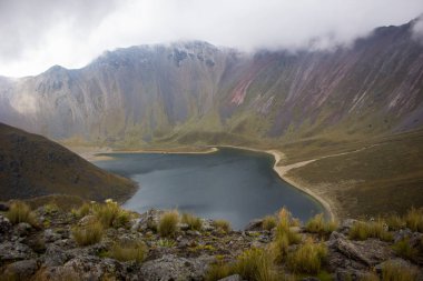 Sis, kayalar ve çimlerle kaplı inanılmaz bir dağ gölünde yürüyüş. Sis, kayalar ve çimlerle.