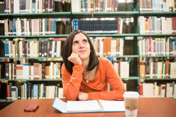 I biblioteket - ganska kvinnlig student som tänker arbeta i en hig — Stockfoto