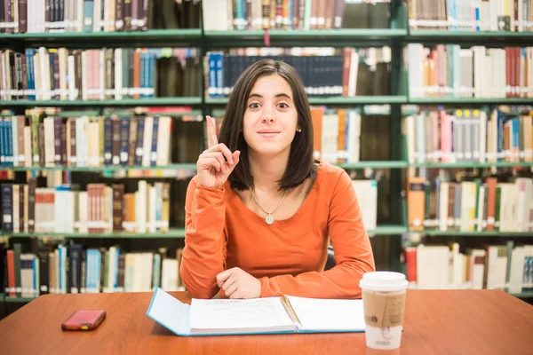 В библиотеке - симпатичная студентка, думающая, работающая в библиотеке. — стоковое фото