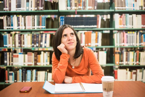 In the library - pretty female student thinking working in a hig — Stock Photo, Image