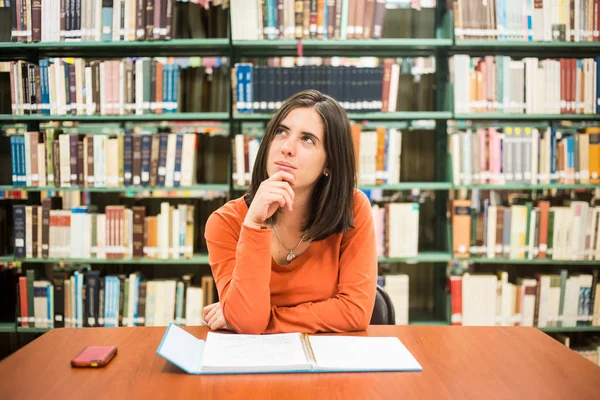 En la biblioteca - estudiante bastante femenina pensando en trabajar en un hig —  Fotos de Stock