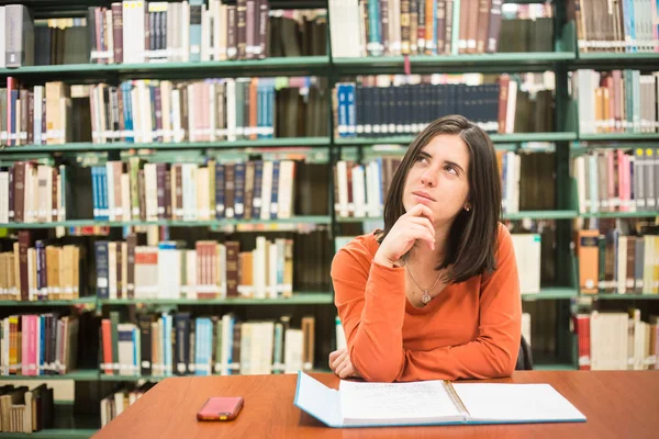 En la biblioteca - estudiante bastante femenina pensando en trabajar en un hig —  Fotos de Stock