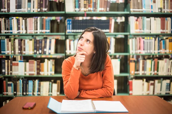 У бібліотеці - гарне жіноче мислення, що працює у високому — стокове фото