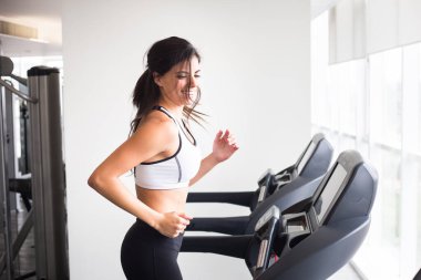 Genç, gülümseyen bir kadın spor salonunda çalışıyor sağlıklı bir yaşam tarzı..