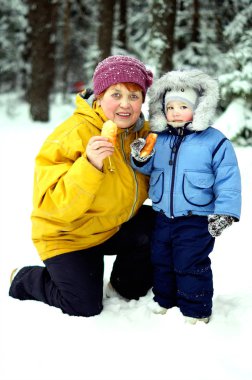 An elderly woman and kid in winter forest clipart
