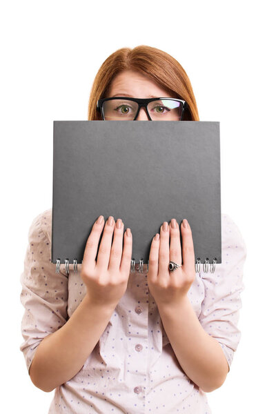 Worried female student hiding behind a book