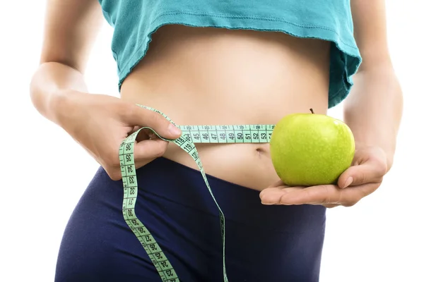 Fit girl measuring her waist and holding green apple — ストック写真