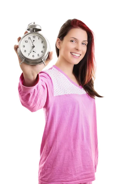 Young woman in pajamas holding alarm clock and smiling — ストック写真
