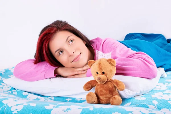 Menina bonita em pijama com seu ursinho de pelúcia sonhando acordado — Fotografia de Stock