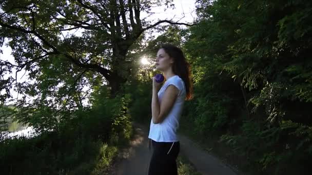Веселая девушка поднимает гантели в парке — стоковое видео