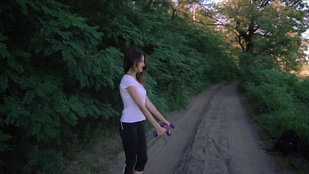 Menina alegre levantando halteres no parque — Vídeo de Stock