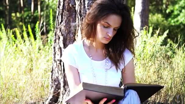 Hermosa joven está leyendo un libro al aire libre . — Vídeo de stock