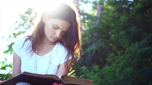 Hermosa joven está leyendo un libro al aire libre . — Vídeo de stock