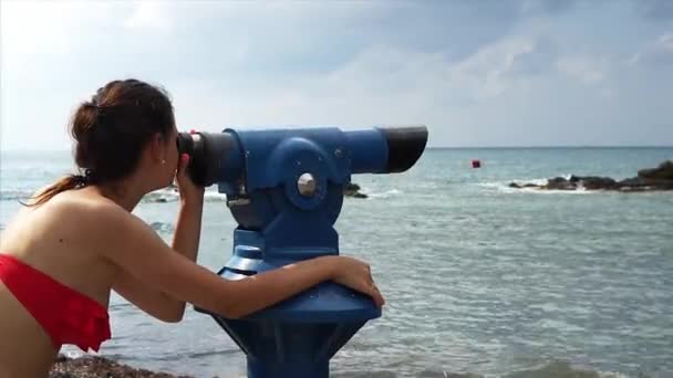 Young woman looking through a coin operated binoculars. — Stock Video