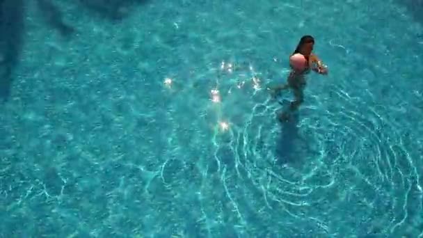Mujer joven jugando con pelota en la piscina — Vídeo de stock