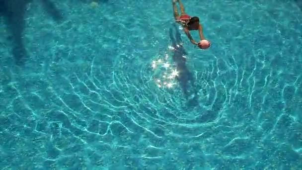 Ung kvinna leker med boll på poolen — Stockvideo