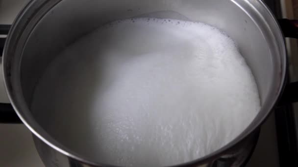 Кипящее молоко на газовой плите, кипящее молоко в кастрюле на плите и течет — стоковое видео