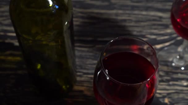 Botella y copa de vino tinto sobre una mesa de madera — Vídeo de stock