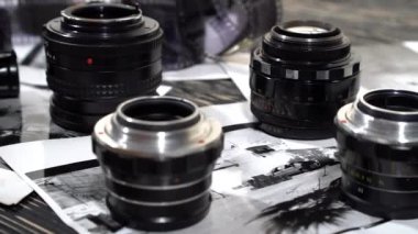 Vintage 35mm kameralar, lensler, fotoğraf ve film yığılı.