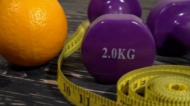 Portakal, suyu, halter ve ahşap arka plan üzerinde ölçüm bandı.