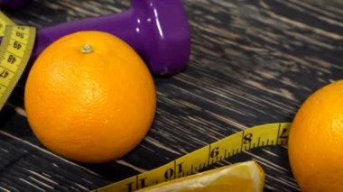 Portakal, suyu, halter ve ahşap arka plan üzerinde ölçüm bandı.