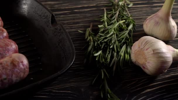 Rohe Würste mit Knoblauch, Rosmarin auf Holzoberfläche — Stockvideo