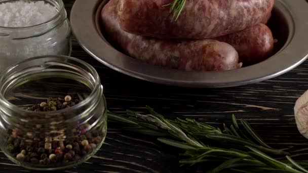 Rohe Würste mit Knoblauch, Rosmarin auf Holzoberfläche — Stockvideo