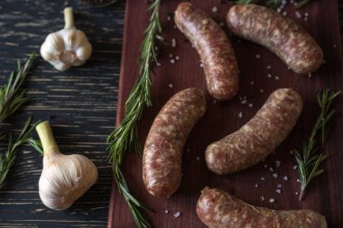 Çiğ sosis ile sarımsak, biberiye ahşap yüzey üzerinde