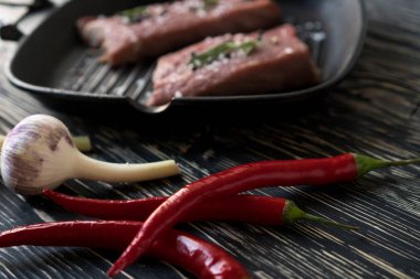 dökme demir tavada sarımsak ve biber ile çiğ biftek.