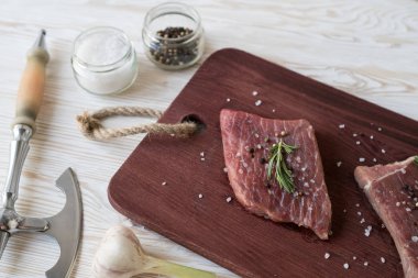 Taze çiğ biftek biberiye ve ahşap masa üzerine sarımsak ile