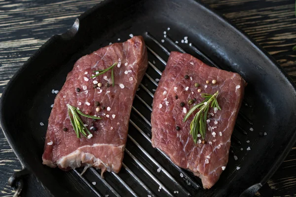 Sartén de carne fresca con romero sobre fondo oscuro, vista superior — Foto de Stock