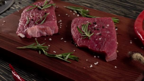 Beef fillet on a desk with pepper, rosemary axe and garlic. — Stock Video