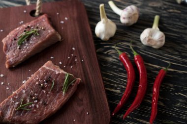 Biberiye, biber ve sarımsak ahşap masa ile taze çiğ biftek