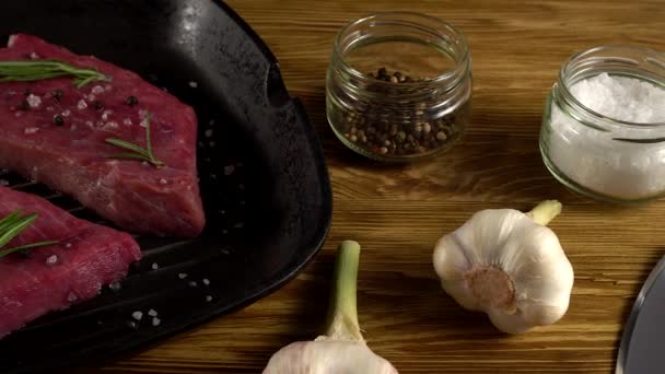 Filete de res en una sartén con pimienta, romero, hacha y ajo . — Vídeos de Stock