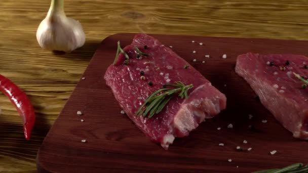 Rundvlees filet op een bureau met peper, rozemarijn en knoflook. — Stockvideo