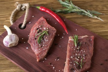 Biberiye, biber ve sarımsak ahşap masa ile taze çiğ biftek